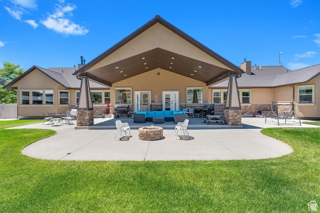 rear view of house with a lawn, a patio, and an outdoor living space with a fire pit