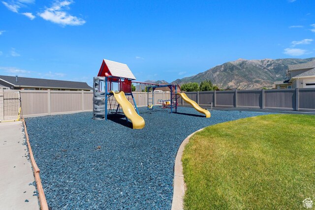 view of playground featuring a lawn and a mountain view