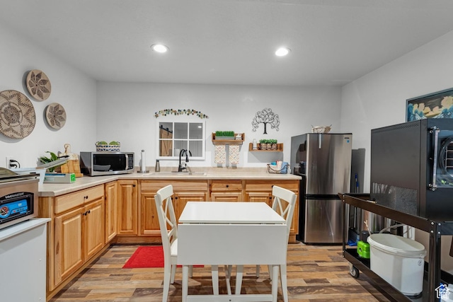 kitchen with light brown cabinets, light wood-type flooring, stainless steel appliances, and sink