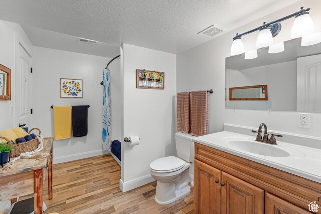 bathroom featuring vanity, a textured ceiling, wood-type flooring, toilet, and curtained shower