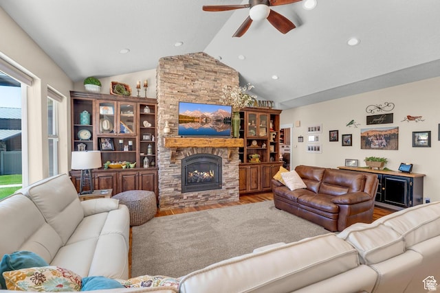 living room featuring ceiling fan, light hardwood / wood-style floors, a fireplace, and vaulted ceiling