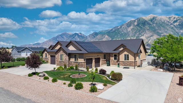 view of front of home featuring solar panels, a garage, a mountain view, and a front lawn
