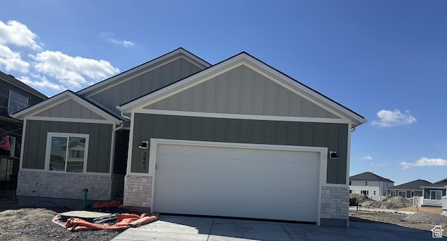 view of front facade featuring a garage, stone siding, board and batten siding, and driveway