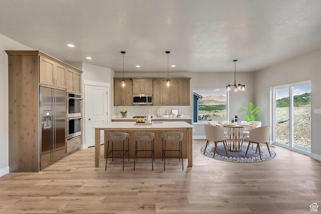 5401 N Orville St Unit 426, Eagle Mountain, UT 84005 - kitchen with a center island with sink, a kitchen bar, light countertops, appliances with stainless steel finishes, and light wood-style floors