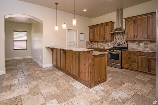 2596 S Little Valley Rd, St George, UT 84790 - kitchen featuring stainless steel range with gas cooktop, wall chimney range hood, decorative light fixtures, light stone counters, and a breakfast bar area