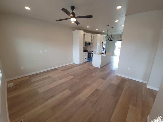unfurnished living room with light hardwood / wood-style flooring, ceiling fan, and sink
