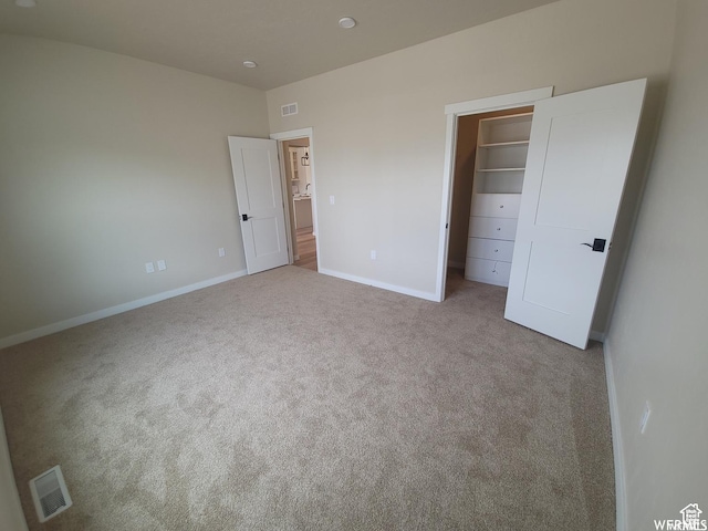 unfurnished bedroom with light colored carpet, a spacious closet, and a closet