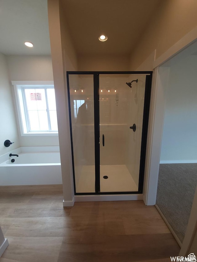 bathroom featuring plus walk in shower and wood-type flooring