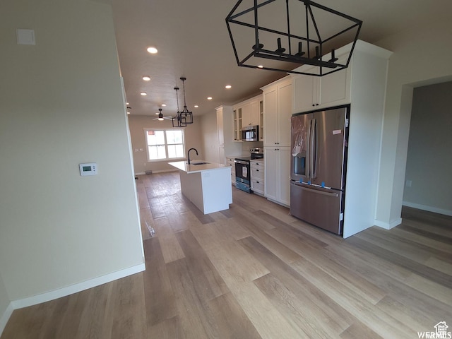 kitchen with white cabinets, sink, hanging light fixtures, an island with sink, and appliances with stainless steel finishes