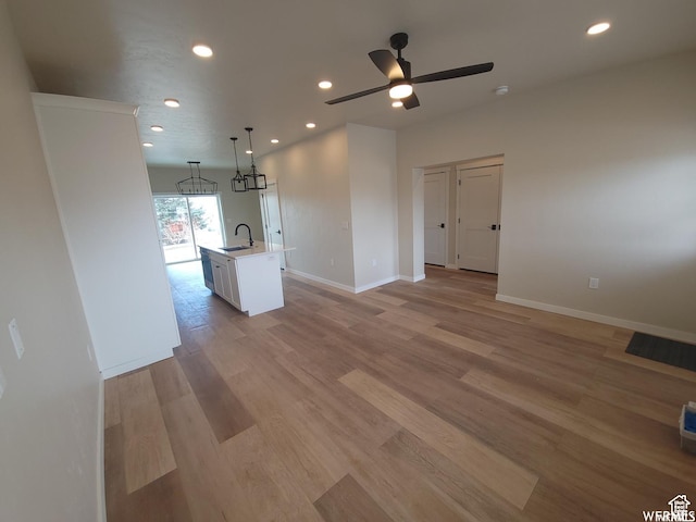 unfurnished living room featuring light wood-type flooring, ceiling fan, and sink
