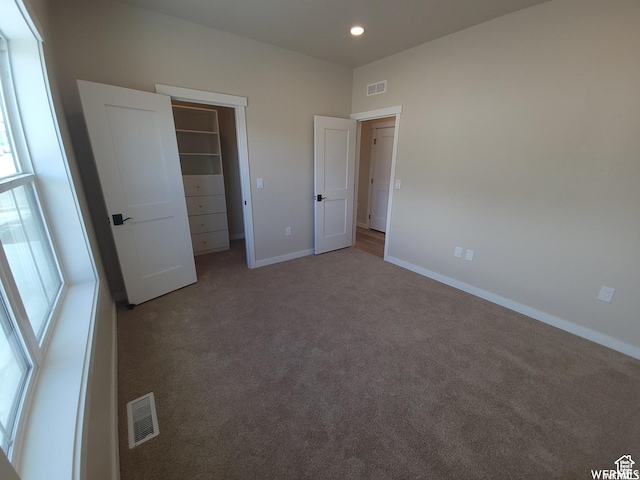 unfurnished bedroom with carpet floors, a spacious closet, and a closet