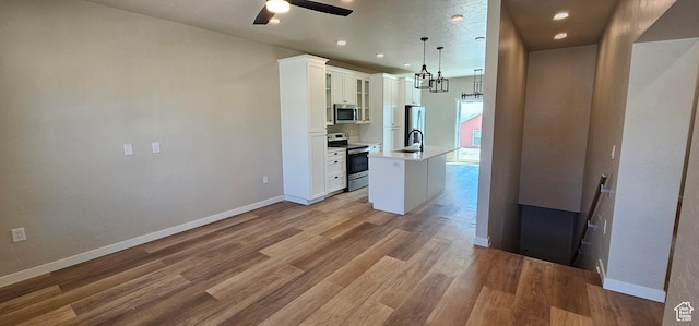 1840 E 840 N Unit 81, Price, UT 84501 - kitchen with white cabinets, an island with sink, hanging light fixtures, and appliances with stainless steel finishes
