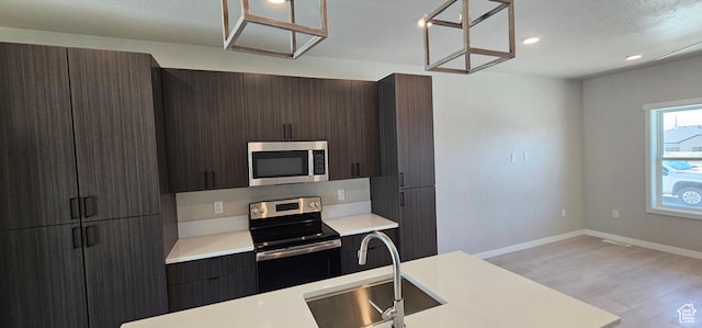 1843 E 840 N Unit 86, Price, UT 84501 - kitchen with sink, hanging light fixtures, light hardwood / wood-style flooring, dark brown cabinets, and appliances with stainless steel finishes