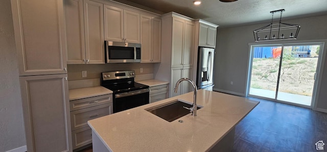 kitchen with sink, stainless steel appliances, a chandelier, pendant lighting, and a kitchen island with sink