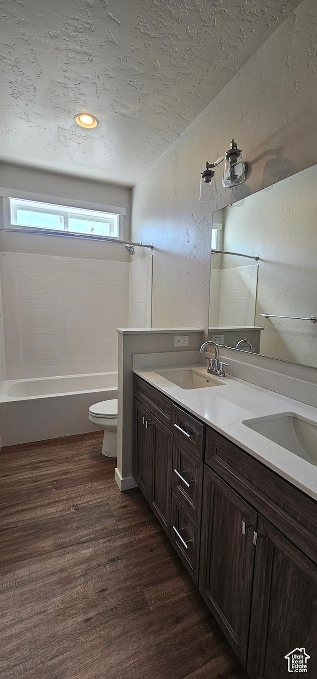 full bathroom featuring hardwood / wood-style floors, vanity, a textured ceiling, and toilet