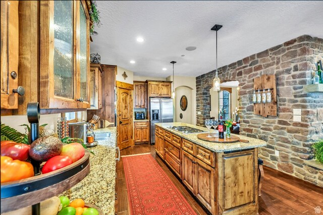 9049 N Timphaven Rd, Sundance, UT 84604 - kitchen featuring dark wood-type flooring, light stone counters, decorative light fixtures, a kitchen island, and appliances with stainless steel finishes