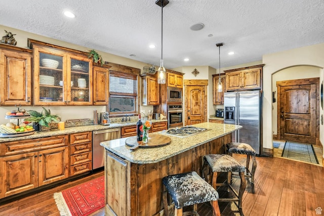 9049 N Timphaven Rd, Sundance, UT 84604 - kitchen with appliances with stainless steel finishes, light stone counters, a breakfast bar, pendant lighting, and a center island