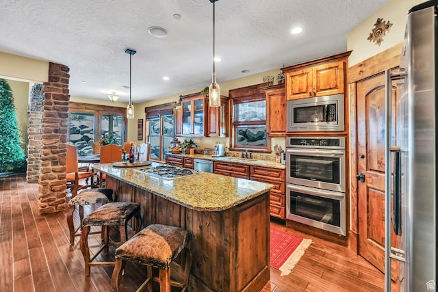 9049 N Timphaven Rd, Sundance, UT 84604 - kitchen with light stone countertops, stainless steel appliances, dark hardwood / wood-style floors, decorative light fixtures, and a kitchen island