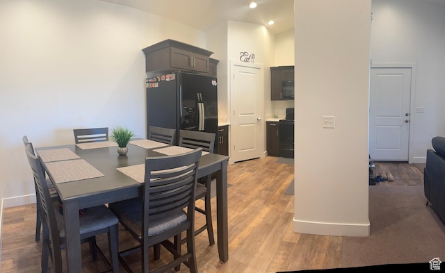 dining space featuring a high ceiling, light wood-style floors, and baseboards