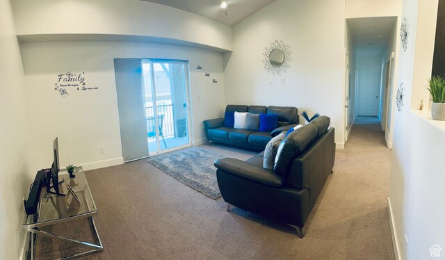 carpeted living area with baseboards and vaulted ceiling