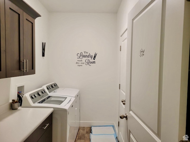 laundry area featuring baseboards, cabinet space, wood finished floors, and washing machine and clothes dryer