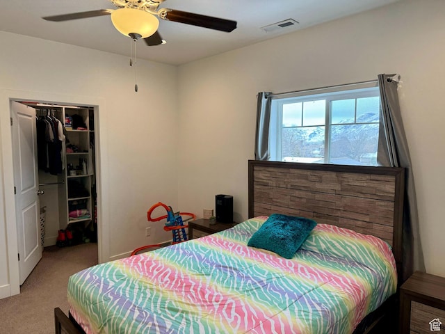 carpeted bedroom featuring a walk in closet, visible vents, a closet, and ceiling fan