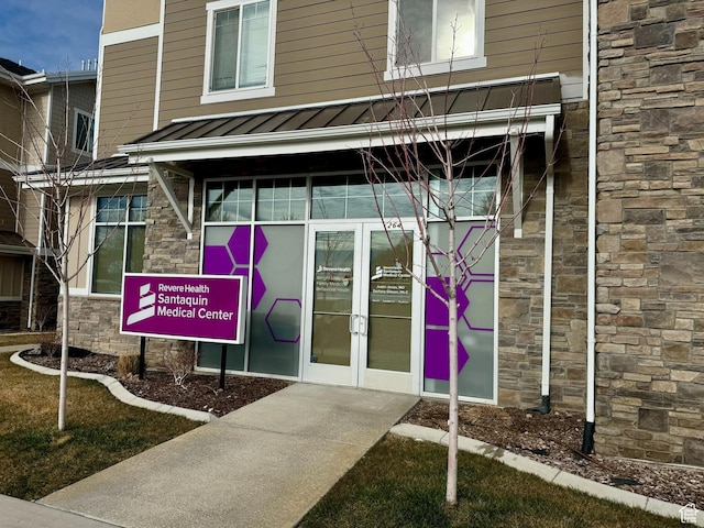 property entrance featuring a standing seam roof, french doors, stone siding, and metal roof