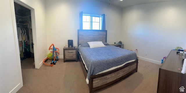 bedroom featuring a closet, baseboards, carpet, and a spacious closet