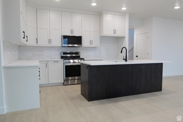 715 E 1250 S, Hyrum, UT 84319 - kitchen featuring appliances with stainless steel finishes, a sink, light wood-type flooring, white cabinets, and light countertops