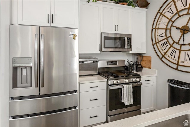 kitchen featuring light stone countertops, stainless steel appliances, and white cabinetry