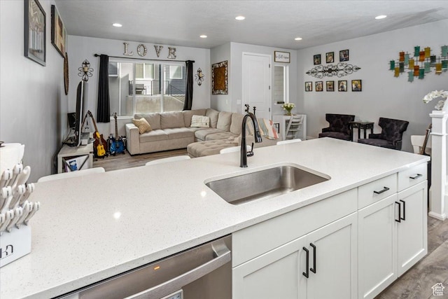kitchen with white cabinets, light hardwood / wood-style flooring, dishwasher, and sink
