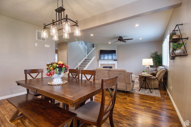 dining room with ceiling fan, dark wood-type flooring, and a brick fireplace