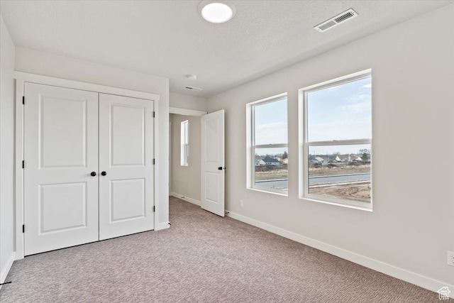 unfurnished bedroom with baseboards, carpet, and a closet