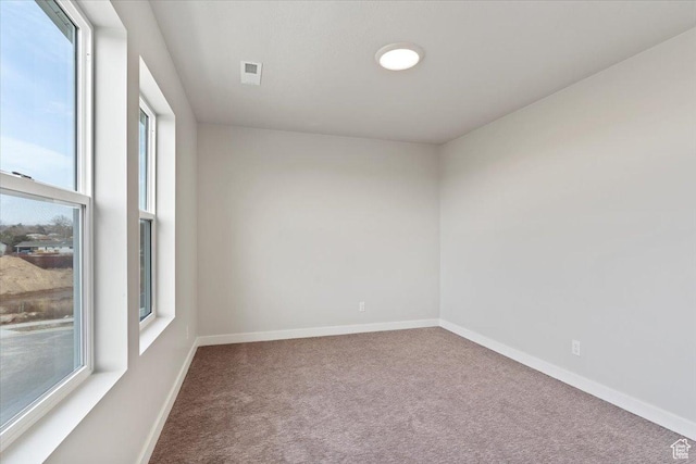 carpeted empty room featuring baseboards