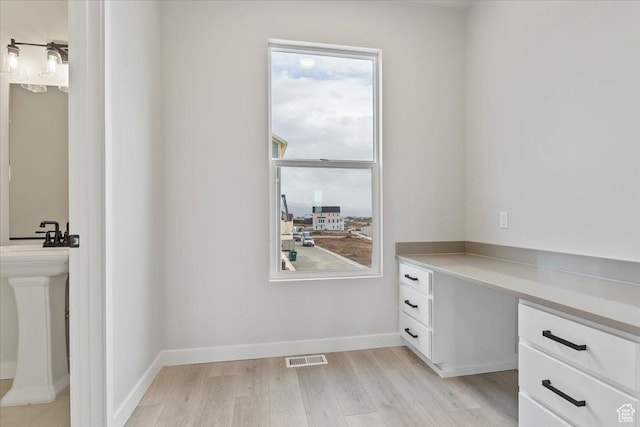 unfurnished office featuring light wood-type flooring and baseboards