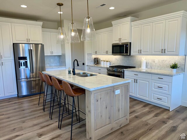 3235 S Retreat Dr, Hurricane, UT 84737 - kitchen with white cabinetry, sink, light stone counters, an island with sink, and high end appliances