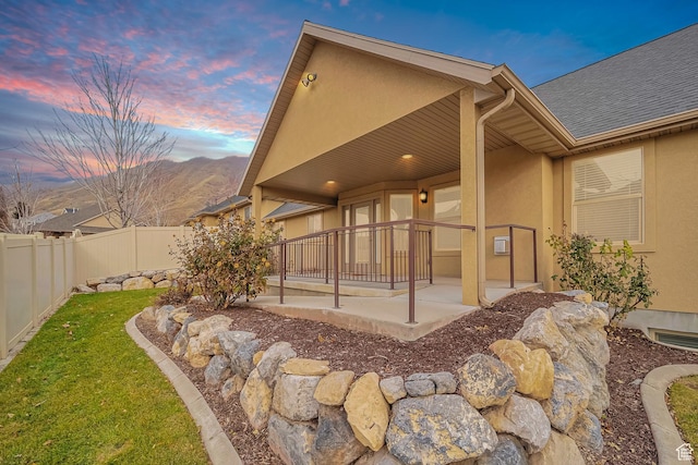 893 N 400 E, Springville, UT 84663 - back of house at dusk featuring stucco siding, a fenced backyard, roof with shingles, and a mountain view