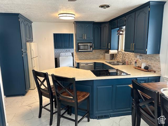 2429 W 300 N, West Point, UT 84015 - kitchen featuring sink, stainless steel appliances, separate washer and dryer, blue cabinets, and kitchen peninsula