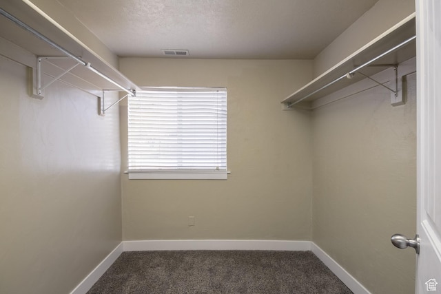 walk in closet featuring dark colored carpet