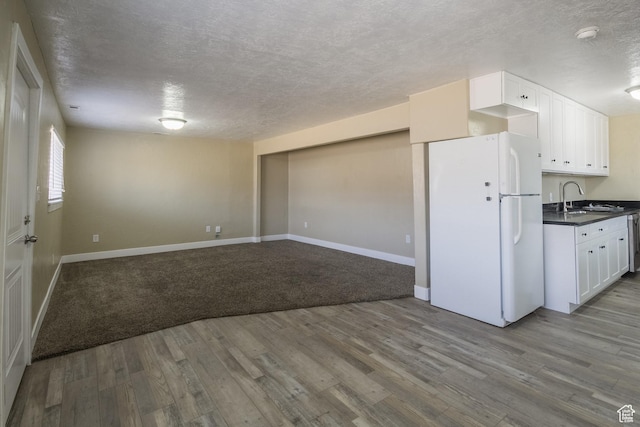 kitchen featuring white cabinetry, sink, white refrigerator, light hardwood / wood-style floors, and a textured ceiling