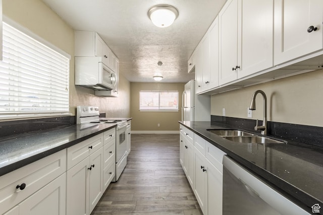 kitchen with white appliances, a textured ceiling, sink, white cabinets, and hardwood / wood-style floors