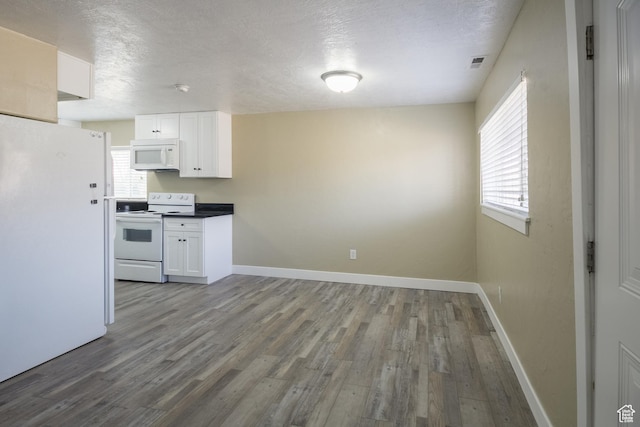 kitchen featuring plenty of natural light, white cabinets, and white appliances