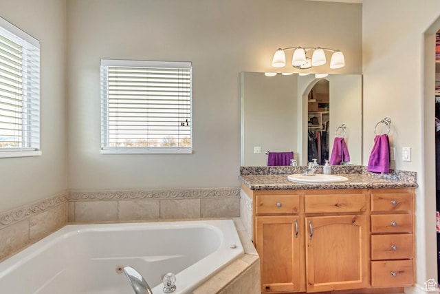 563 W Kalia Cv, Murray, UT 84123 - bathroom featuring tiled tub, plenty of natural light, and vanity