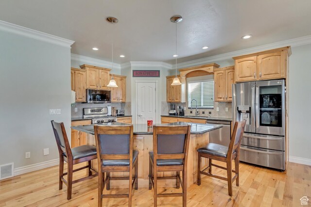 563 W Kalia Cv, Murray, UT 84123 - kitchen with a breakfast bar, a center island, light wood-type flooring, ornamental molding, and appliances with stainless steel finishes