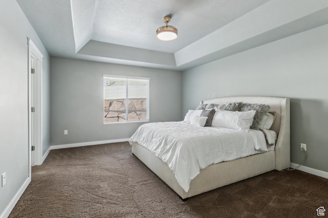 bedroom featuring a textured ceiling, carpet flooring, a raised ceiling, and baseboards