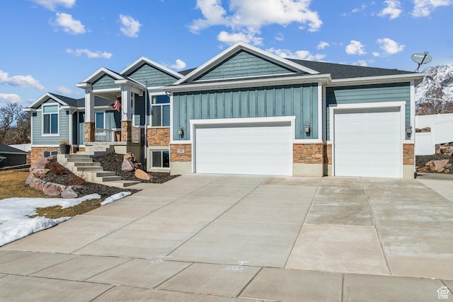 view of front of property featuring concrete driveway, stone siding, board and batten siding, and an attached garage