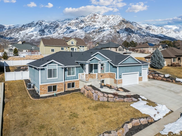 view of front of home featuring a mountain view, central AC, fence, stone siding, and driveway