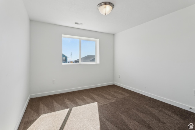 empty room with carpet, visible vents, and baseboards