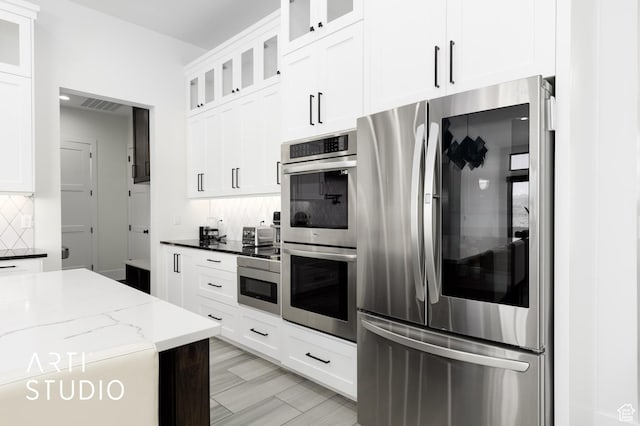 5090 W 3175 S, Hurricane, UT 84737 - kitchen featuring backsplash, dark stone counters, light wood-type flooring, appliances with stainless steel finishes, and white cabinetry
