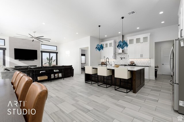 5090 W 3175 S, Hurricane, UT 84737 - kitchen featuring stainless steel fridge, white cabinetry, hanging light fixtures, a breakfast bar area, and an island with sink